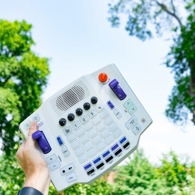 Blipblox myTRACKS held up outdoors against a bright blue sky and trees