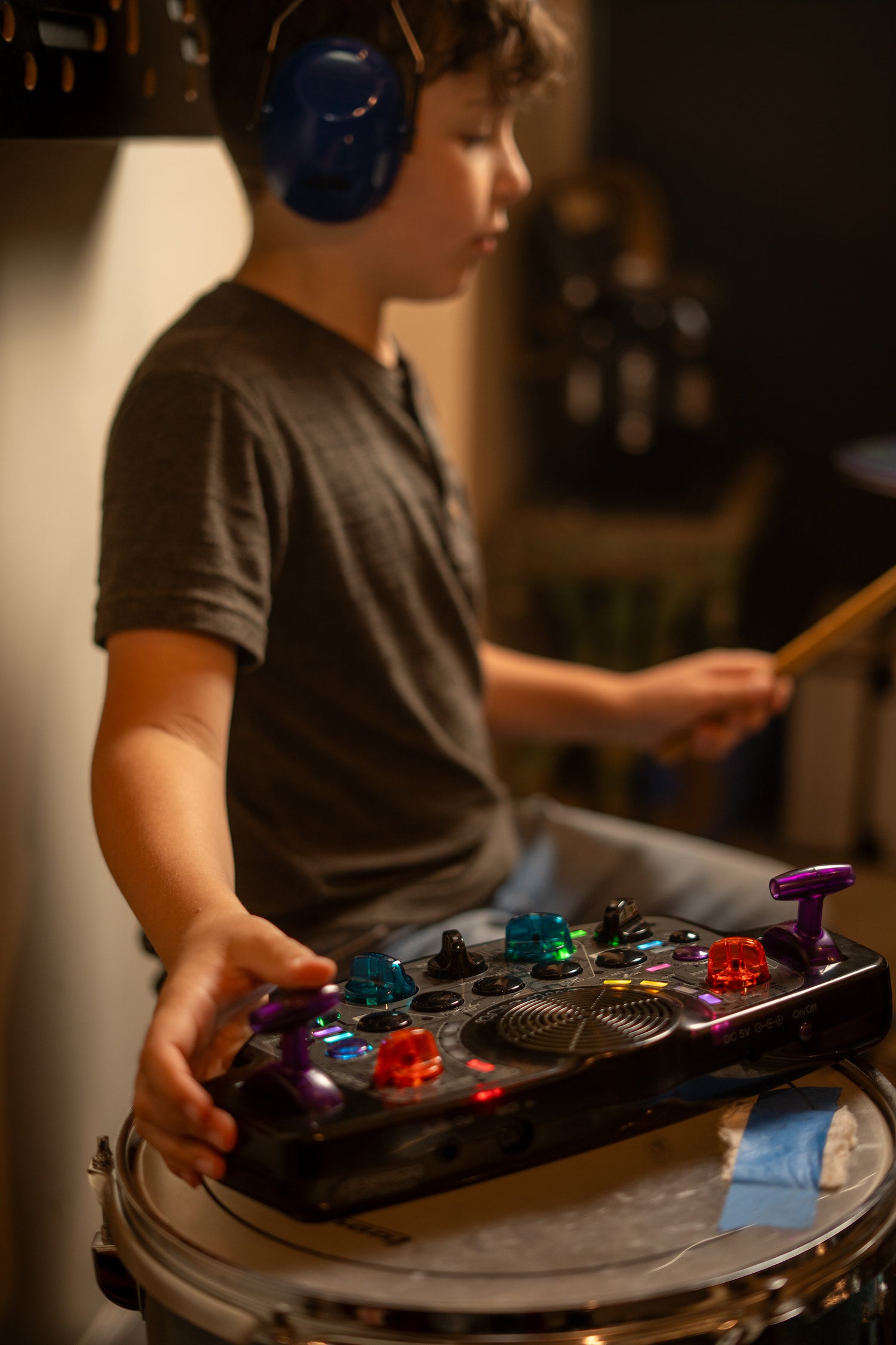 Kid playing a drum kit and Blipblox After Dark while wearing headphones