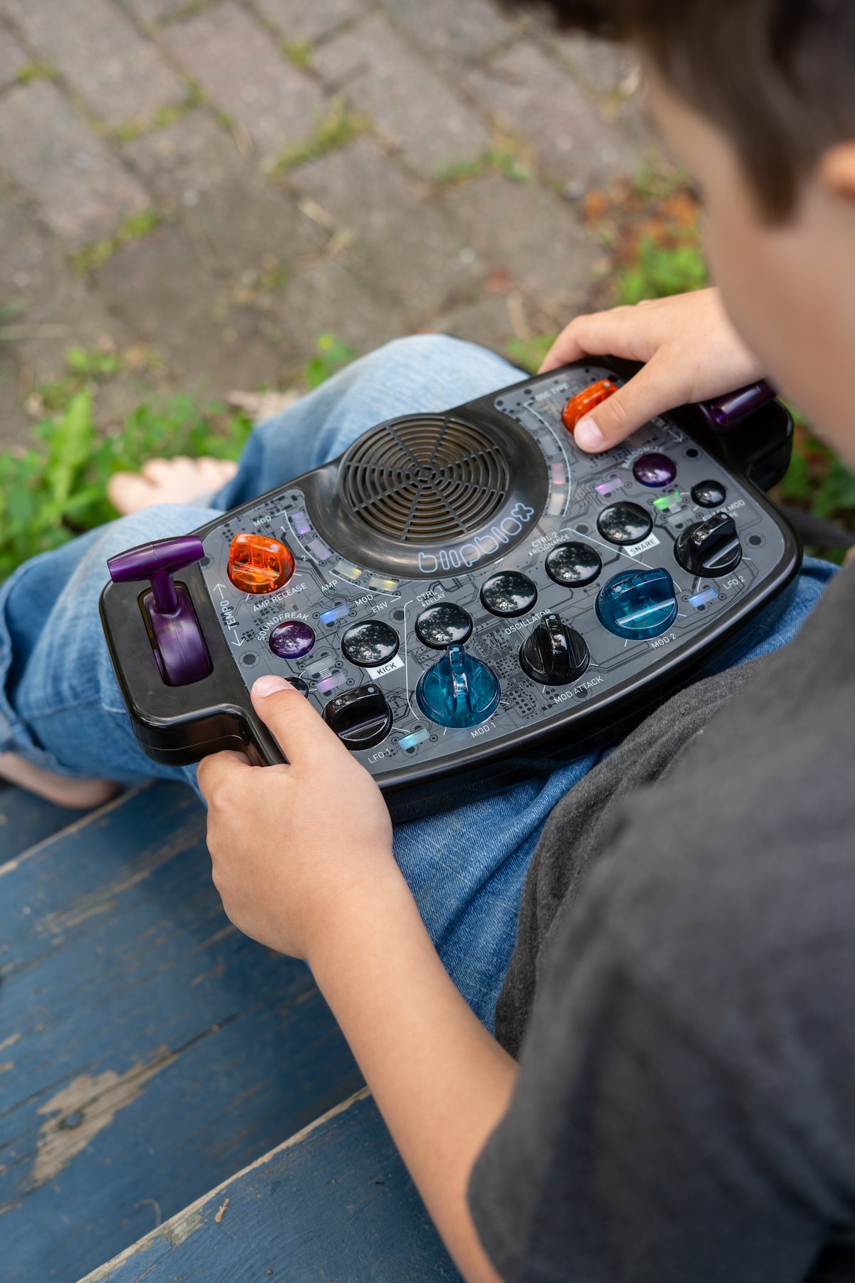 Child playing with a Blipblox After Dark synth outdoors