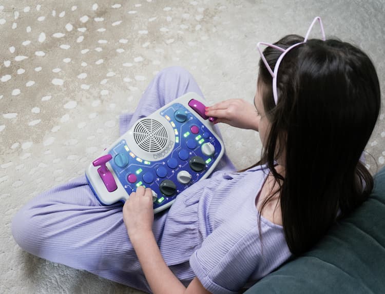 Child playing with a Blipblox SK2 synthesizer on a rug