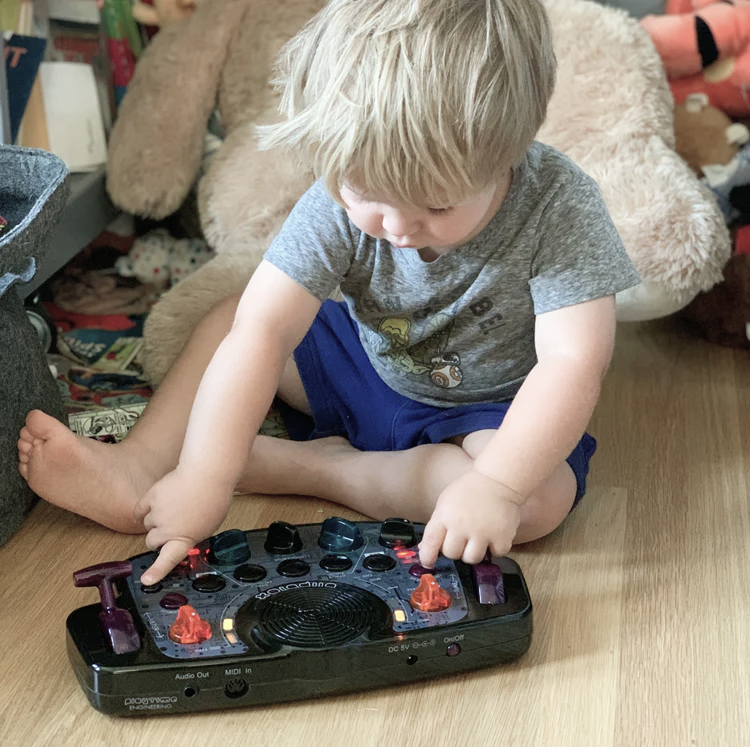 Young child playing with a electronic music toy Blipblox After Dark on the floor