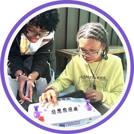 Two children playing with a Blipblox myTRACKS on a table outdoors.
